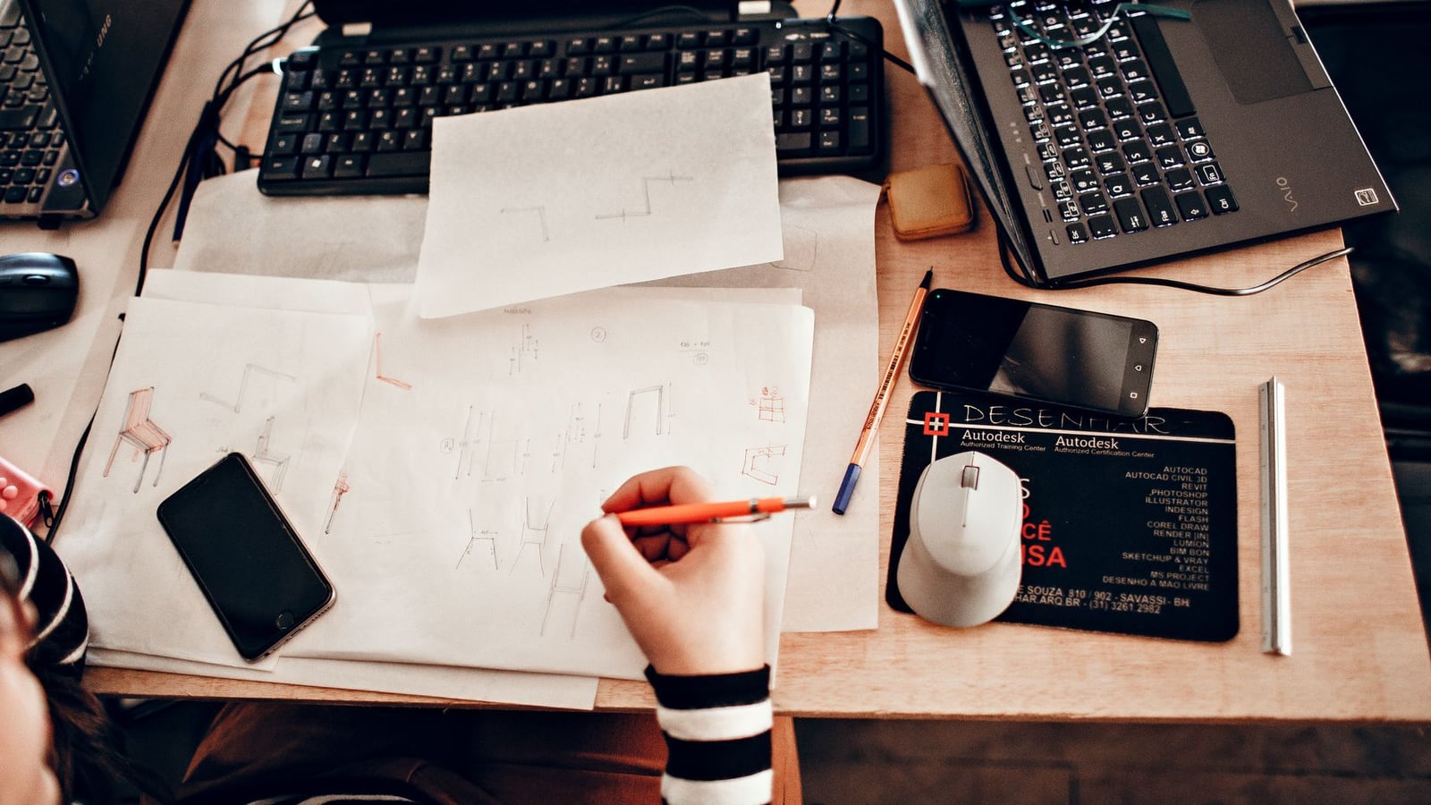 A designer's desk featuring a vector CAD layout on a screen and a physical laser-cut prototype.