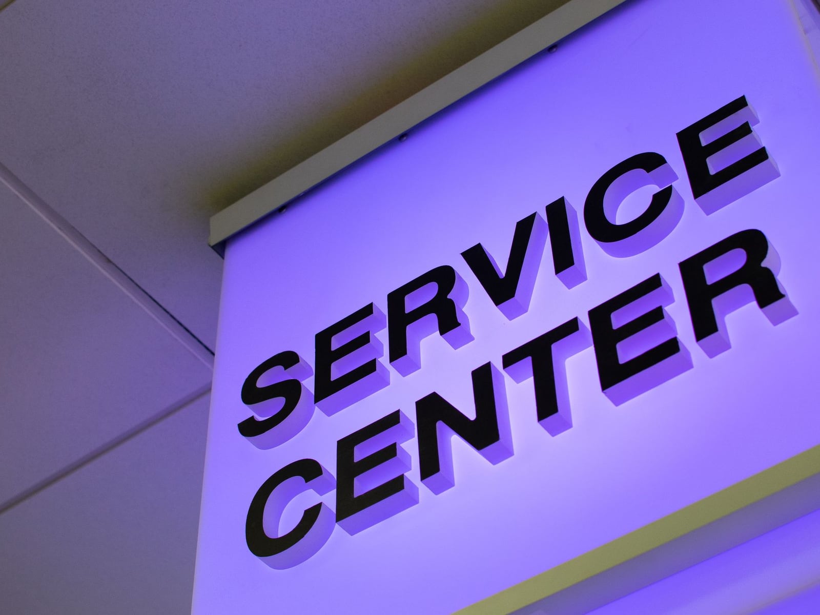 A professional frosted acrylic and aluminium office sign mounted on a contemporary grey wall.